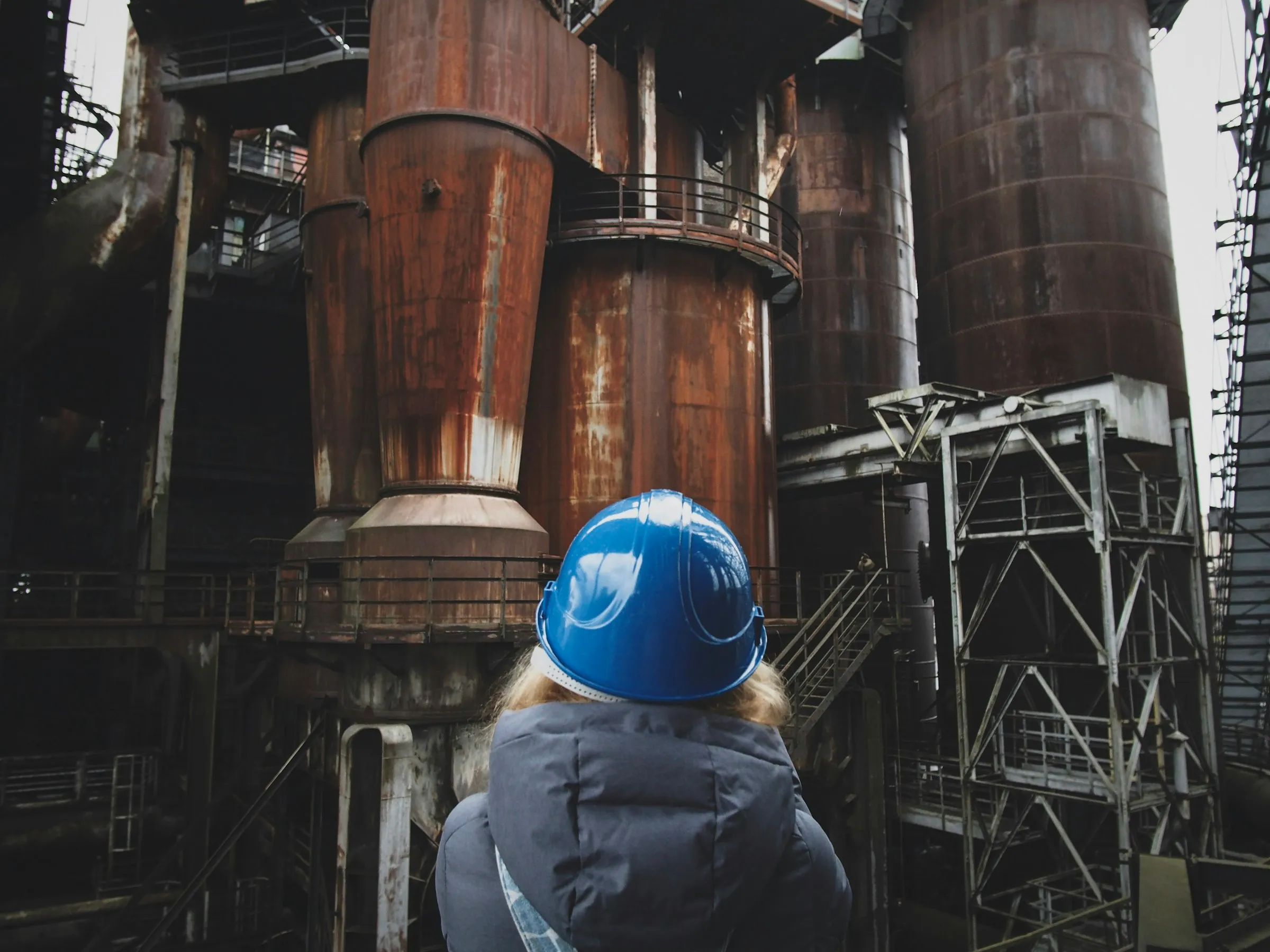 Inspector in a hard hat looking up at an industrial plant