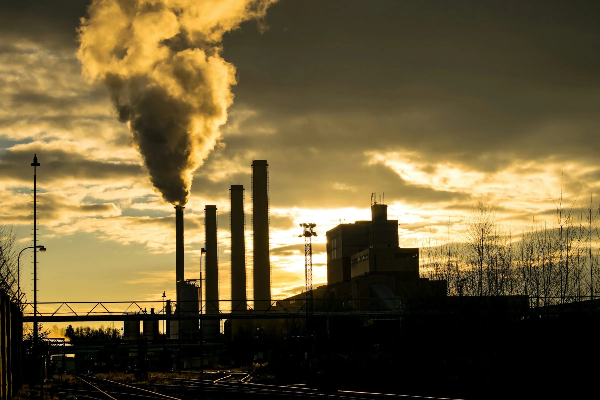 Factory chimneys releasing smoke at sunset