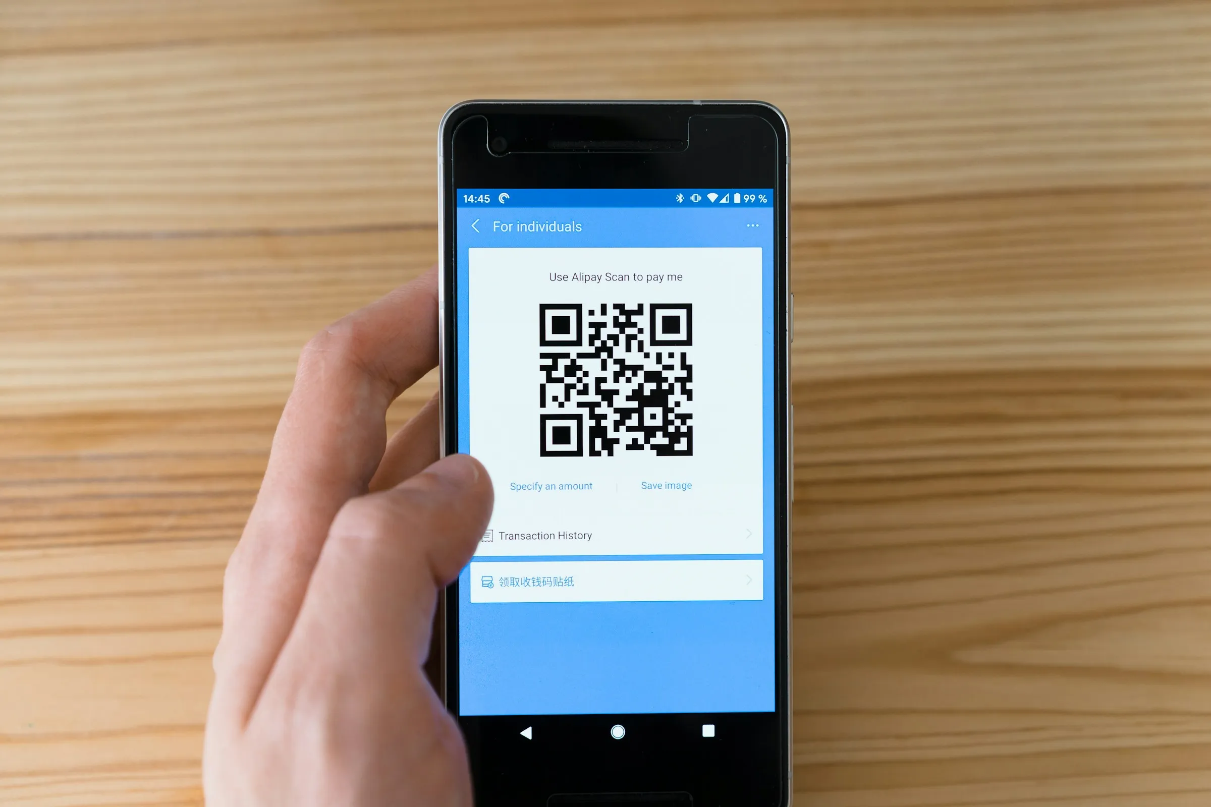 Hand holding a phone showing a QR code