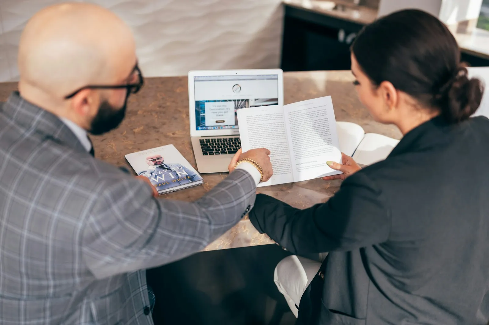 Two business people reviewing documents at a desk with a laptop