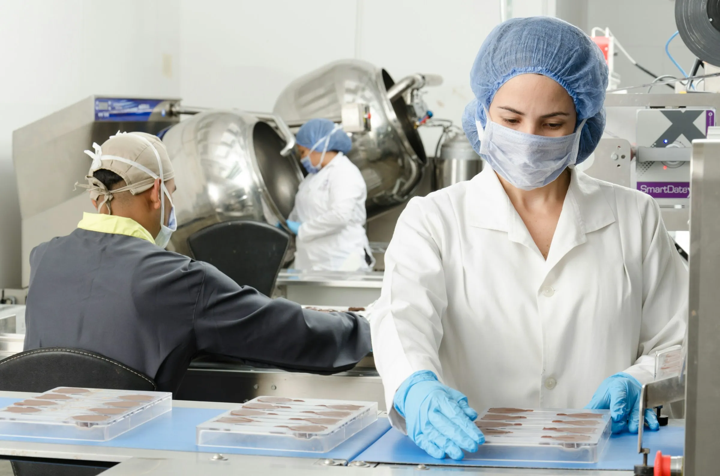 Food production staff in hairnets and gloves packing trays