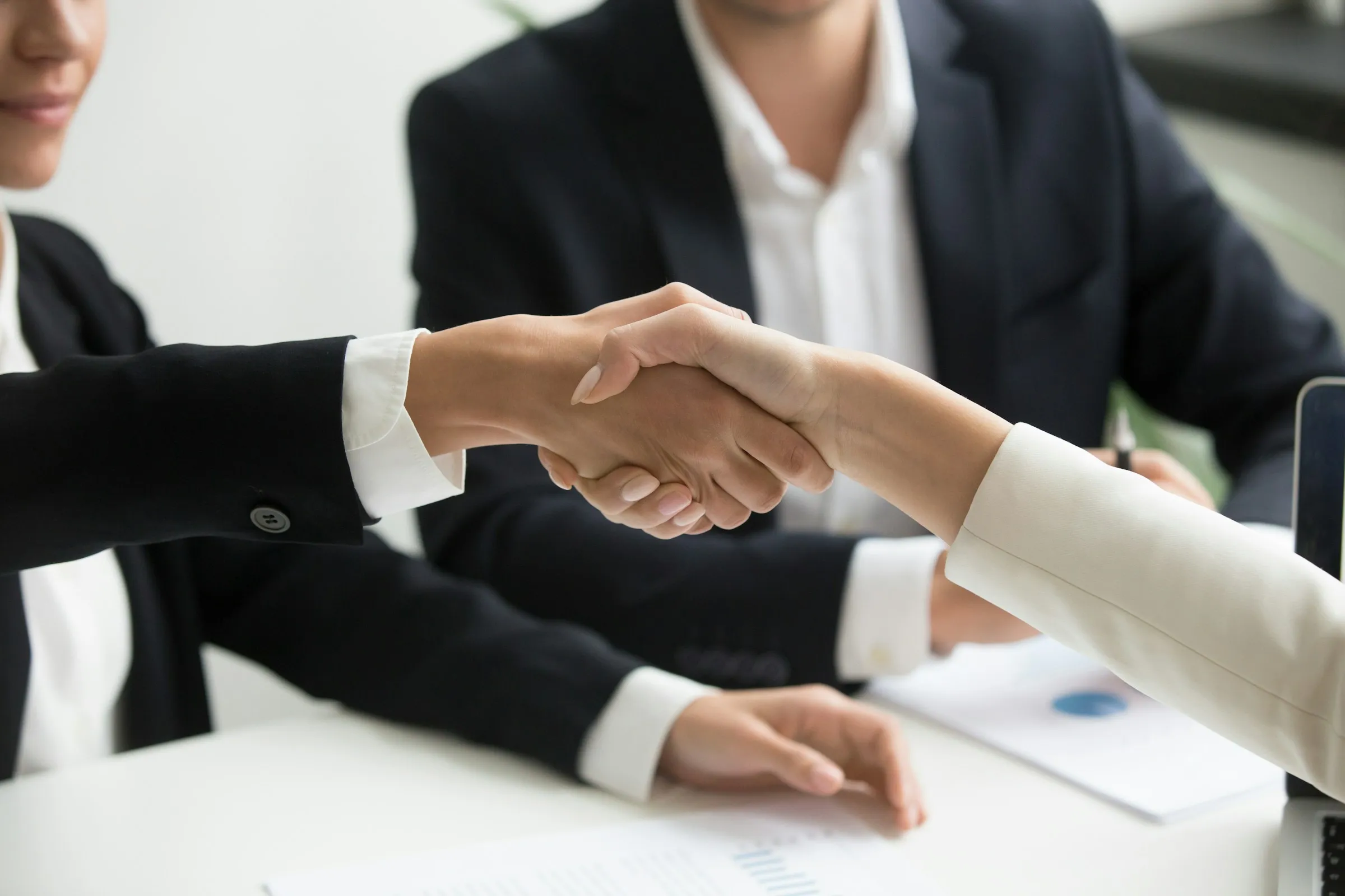 Business partners shaking hands across a meeting table
