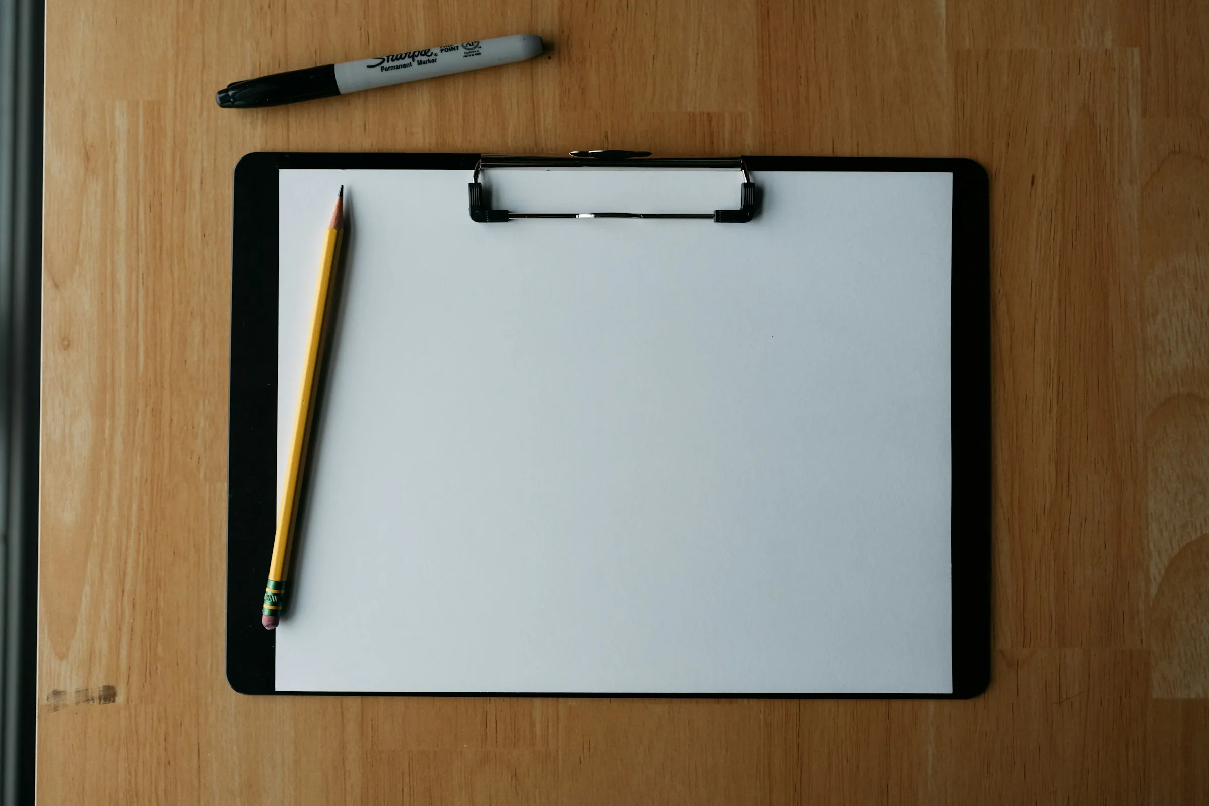 Blank clipboard and pencil on a wooden desk
