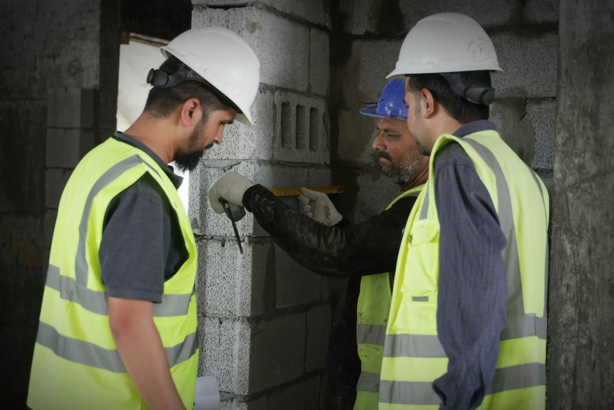 Engineers in hard hats inspecting a building wall